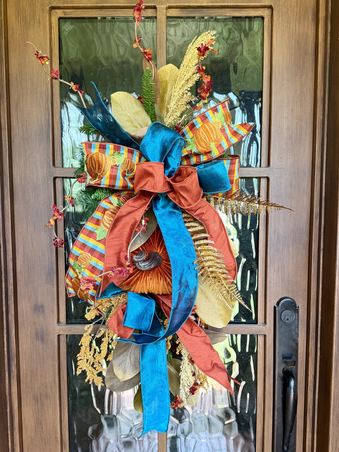 PRE-ORDER | Autumn Jewel Fall Door Swag — handcrafted fall door swag with jewel-toned teal and rust ribbon, velvet pumpkin, magnolia leaves, and metallic gold foliage